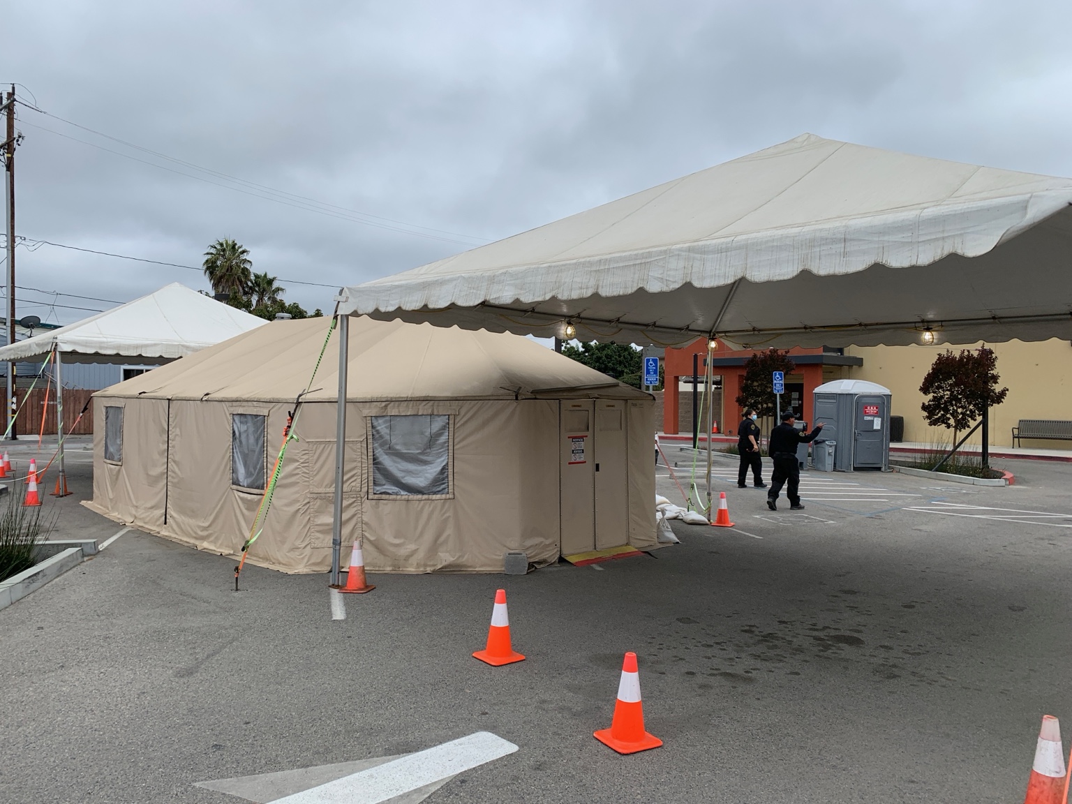 Canopy shelter and adjacent tent installed in a paved work area