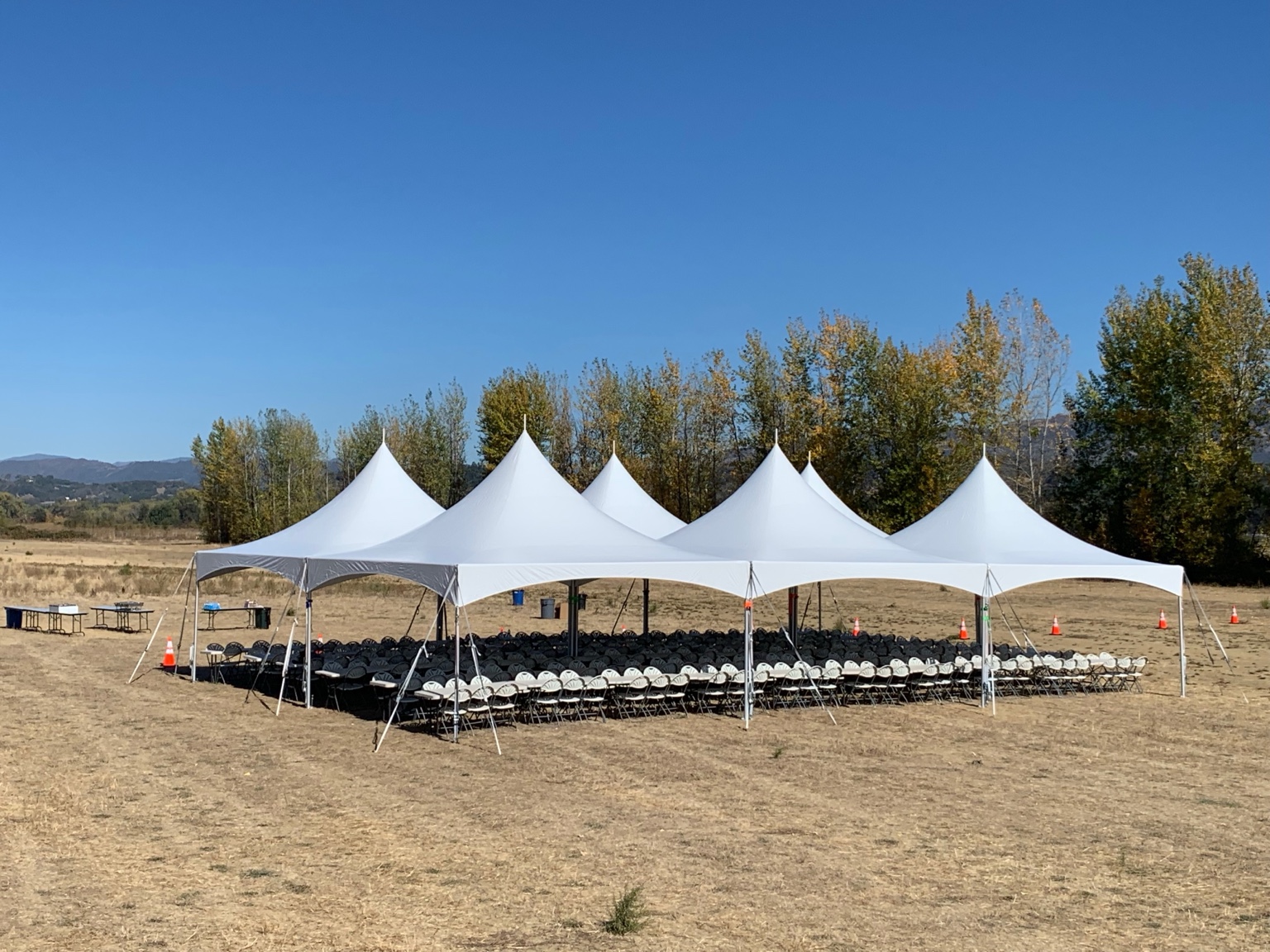 White peaked event canopies providing covered seating for a large group
