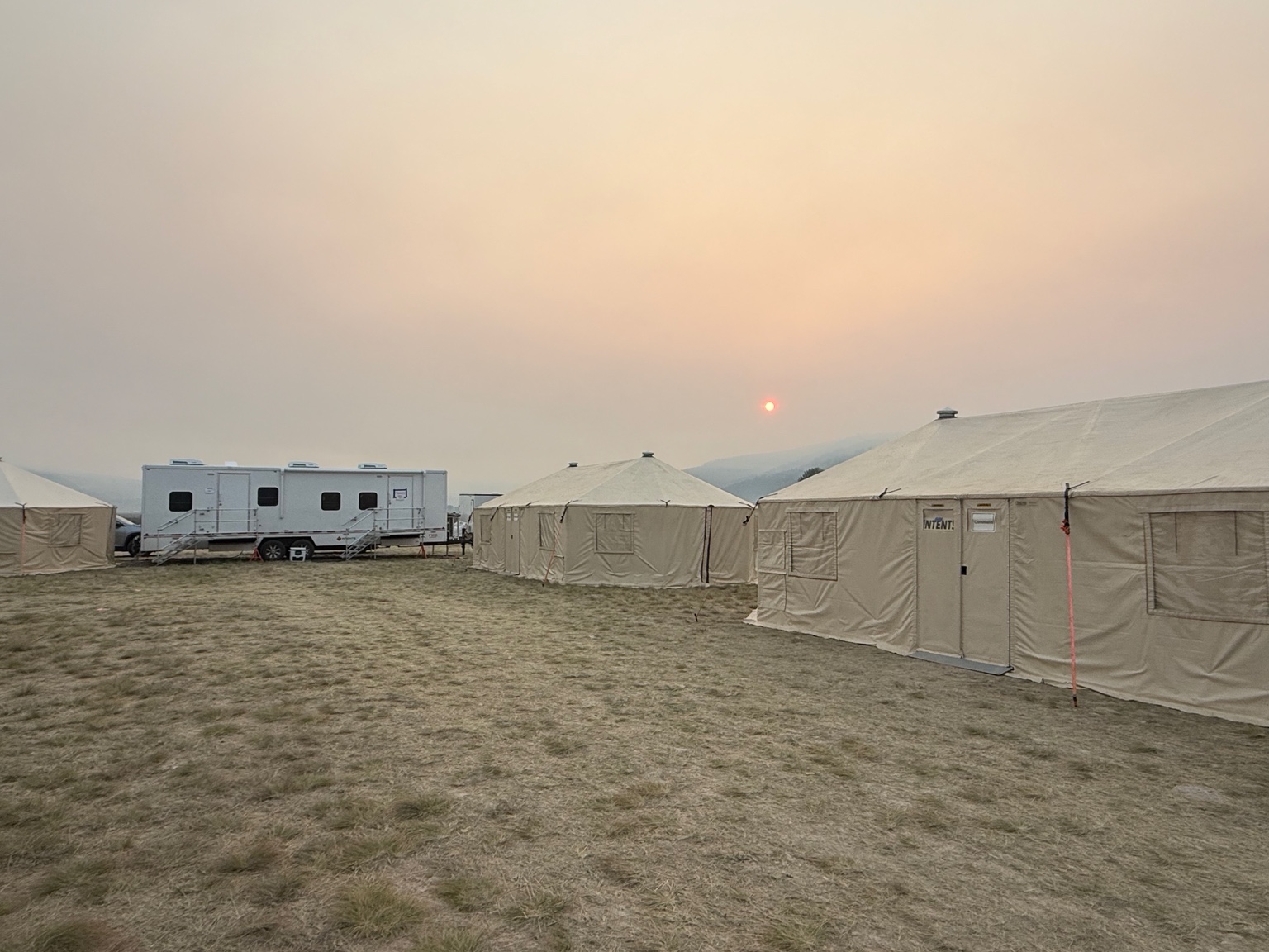 Office trailer and tents at a wildfire support camp at sunset
