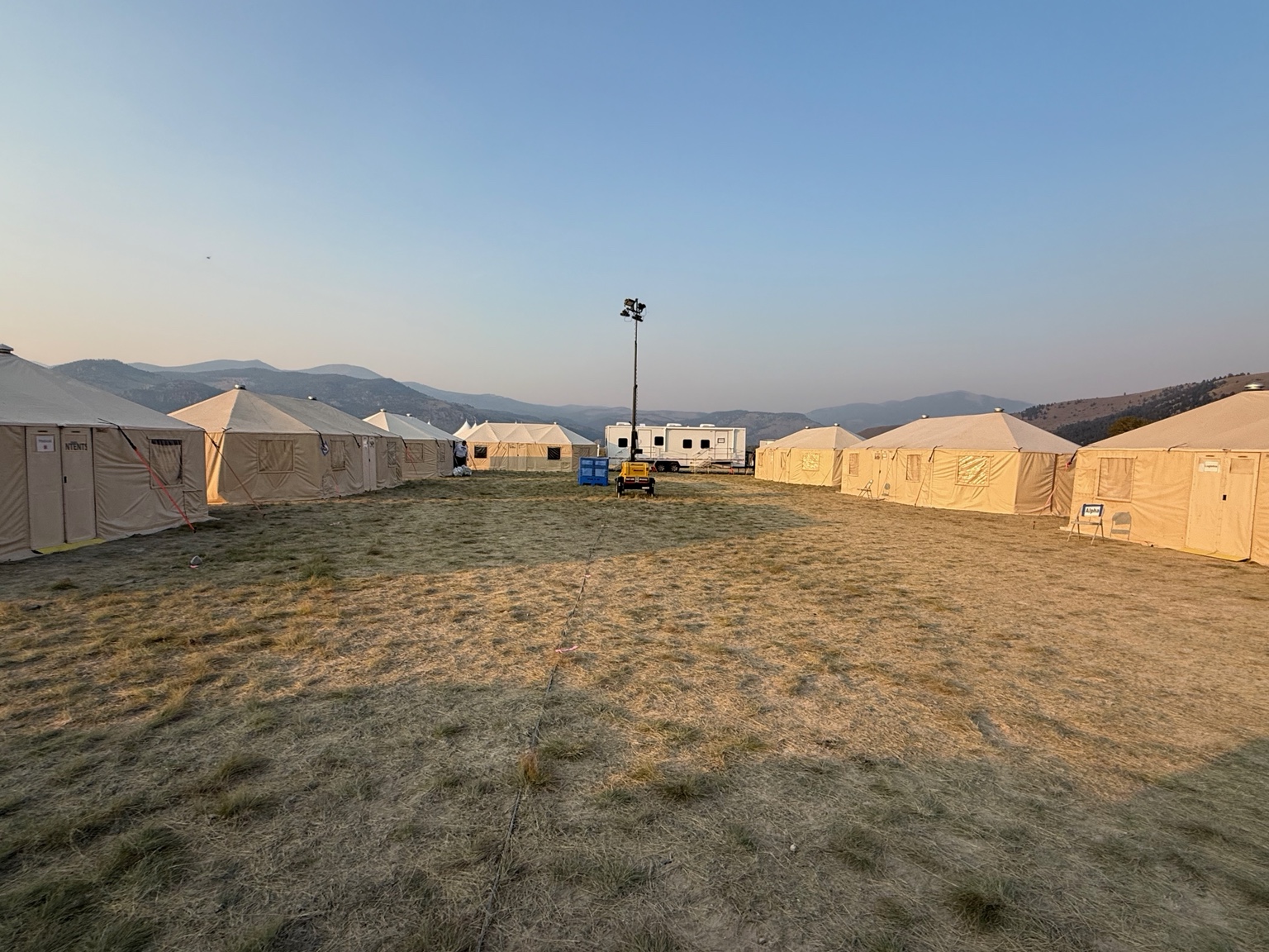 Light tower supporting a large temporary tent camp at dusk